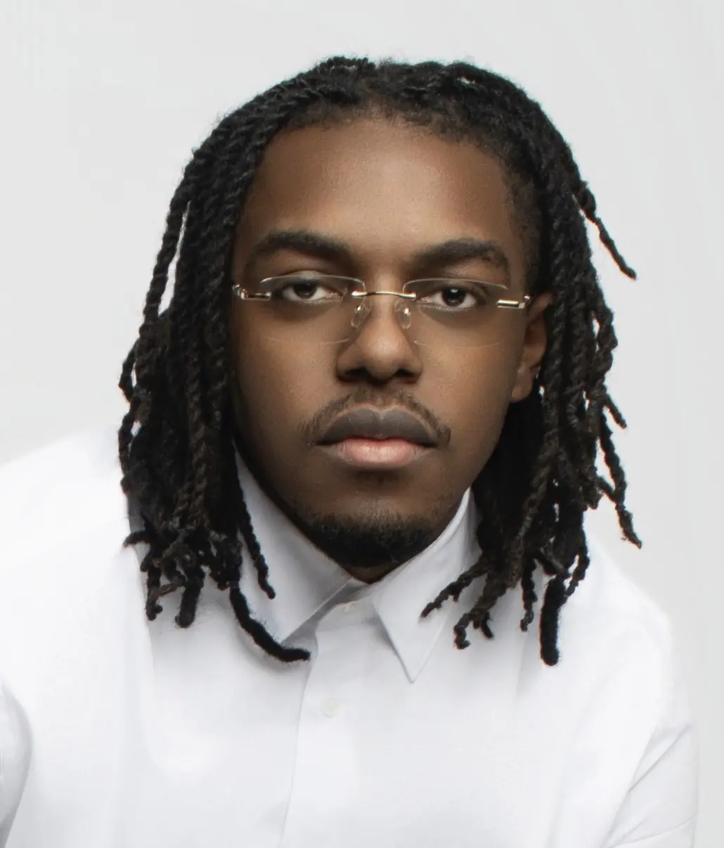 Studio portrait of John Murrel in a white shirt against a light gray wall